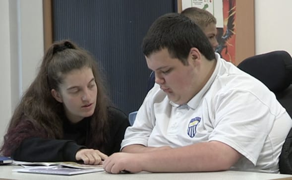 Photograph of young disabled man working with his teacher in an education setting