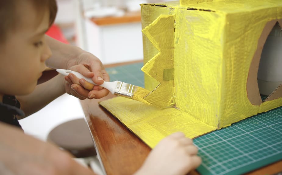 Photograph of a child painting a cardboard box monster