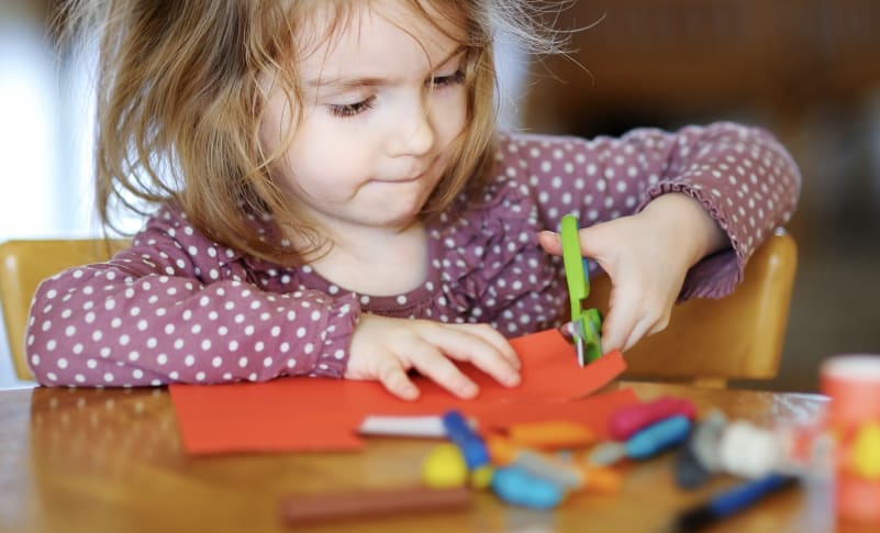 Young child cutting out some coloured paper